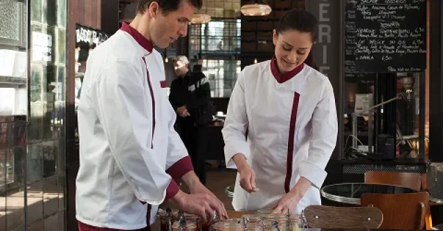 Two people in uniform, handling jars